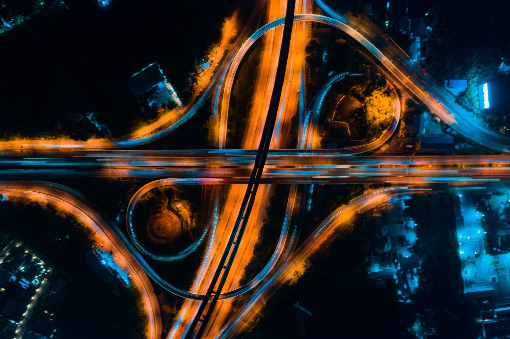 An aerial photograph of a selection of intertwined ring roads, lit up at night.