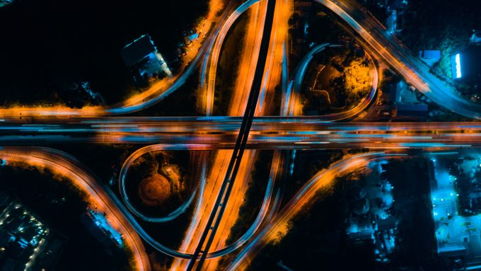 An aerial photograph of a selection of intertwined ring roads, lit up at night.